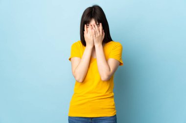 Genç Ukraynalı kız yorgun ve hasta bir ifadeyle mavi arka planda izole edilmiş.