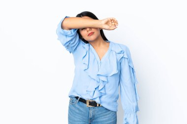 Beyaz arka planda izole edilmiş genç Latin kadın gözlerini elleriyle kapatıyor.