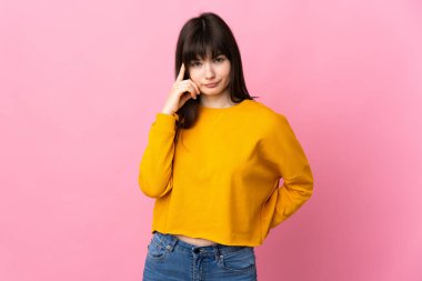 Pembe arka planda izole edilmiş genç Ukraynalı kadın bir fikir düşünüyor.