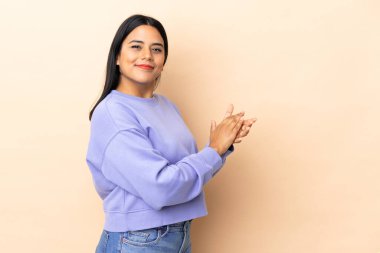 İzole edilmiş arka planda genç Latin bir kadın alkışlıyor.