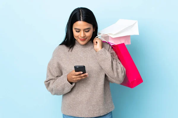 Mujer Latina Joven Aislada Sobre Fondo Azul Sosteniendo Bolsas Compras —  Fotos de Stock