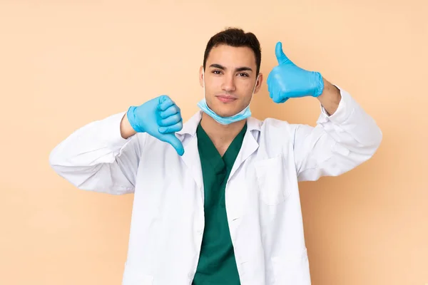 Young dentist man holding tools isolated on beige background making good-bad sign. Undecided between yes or not