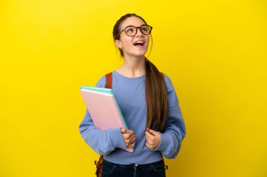 İzole edilmiş sarı arka planda gülen öğrenci bir kadın.