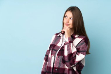 Kafkasyalı genç kız mavi arka planda izole edilmiş ve yukarı bakıyor.