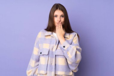 Mor arka planda izole edilmiş, ağzı eliyle kapatan beyaz bir kız.