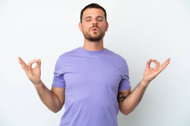 Zen pozisyonunda beyaz arka planda izole edilmiş genç Brezilyalı adam.