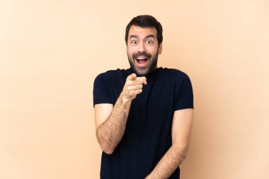 Kafkasyalı yakışıklı, soyutlanmış arka planda şaşırmış ve ön tarafı işaret ediyor.