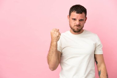 Pembe arka planda mutsuz bir ifadeyle izole edilmiş genç Brezilyalı adam.