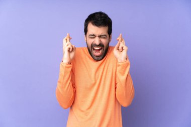 İzole edilmiş mor arka planı olan beyaz tenli yakışıklı bir adam.