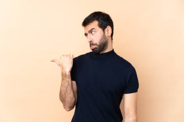 Kafkas yakışıklı adam izole edilmiş arka planda mutsuz ve kenarı işaret ediyor.