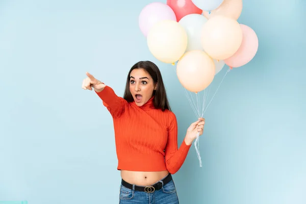 Jeune Femme Attrapant Nombreux Ballons Isolés Sur Fond Bleu Pointant — Photo