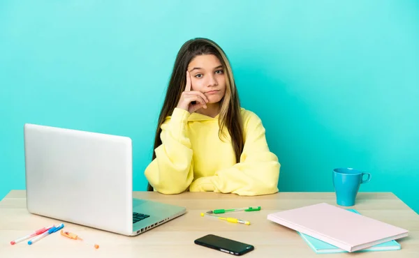 Menina Uma Mesa Com Laptop Sobre Fundo Azul Isolado Pensando — Fotografia de Stock