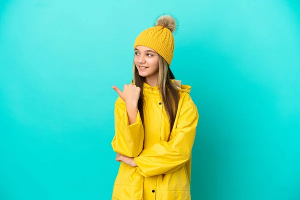 Niña Usando Una Capa Impermeable Sobre Fondo Azul Aislado Apuntando —  Fotos de Stock