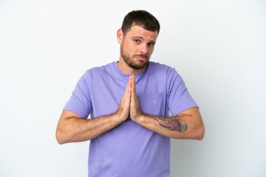 Beyaz arka planda izole edilmiş genç Brezilyalı adam avuç içlerini bir arada tutuyor. İnsan bir şey ister.