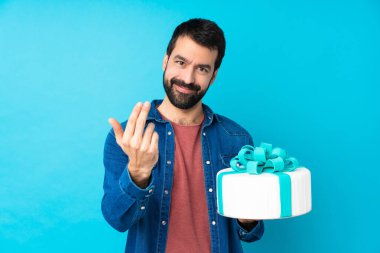 İzole edilmiş mavi arka planda büyük bir pastası olan yakışıklı genç bir adam davet ediyor. Gelmene sevindim.