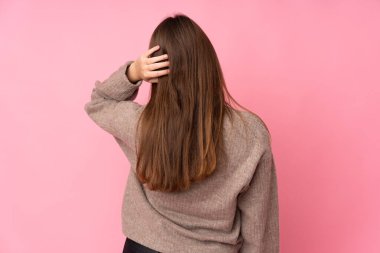 Kafkasyalı genç kız pembe arka planda izole edilmiş ve düşünüyor.