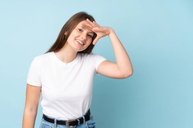 Kafkasyalı genç bir kız mavi arka planda izole edilmiş. Bir şeye bakmak için uzaklara bakıyor.