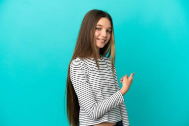 Küçük kız izole edilmiş mavi arka plan geriye işaret ediyor