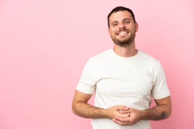 Genç Brezilyalı adam pembe arka planda izole edilmiş gülüyor.