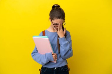 İzole edilmiş sarı arka planda, yorgun ve hasta bir ifadeyle öğrenci bir kadın.