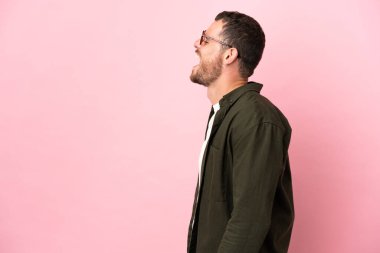 Pembe arka planda izole edilmiş genç Brezilyalı adam yan yana gülüyor.