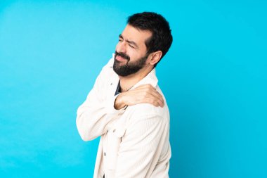 Beyaz kadife ceketli genç ve yakışıklı bir adam izole edilmiş mavi arka plan üzerinde çabaladığı için omuz ağrısından muzdarip.