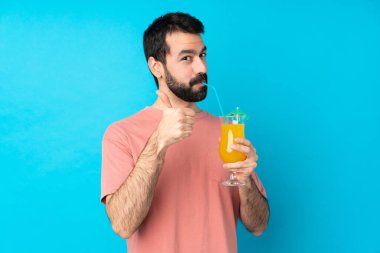 Genç adam mavi arka planda bir kokteyl tutuyor.