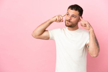 Pembe arka planda izole edilmiş genç Brezilyalı adamın şüpheleri ve düşünceleri var.