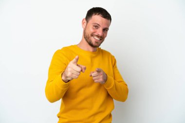 Beyaz arka planda izole edilmiş genç Brezilyalı adam şaşırmış ve ön tarafı işaret ediyor.