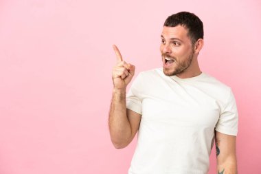 Pembe arka planda izole edilmiş genç Brezilyalı bir adam parmak kaldırarak çözümü anlamaya çalışıyor.