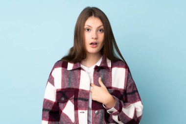 Mavi arka planda izole edilmiş genç beyaz kız kendini işaret ediyor.