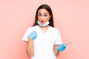 Pembe arka planda yüz ifadesi ile izole edilmiş kadın dişçi aletleri