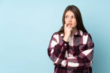 Genç beyaz kız mavi arka planda izole edilmiş gergin ve korkmuş.