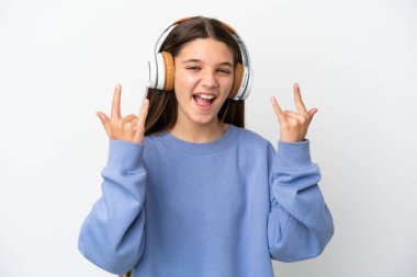 Küçük kız izole edilmiş beyaz arka planda müzik dinliyor, rock hareketleri yapıyor.