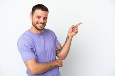 Beyaz arka planda izole edilmiş genç Brezilyalı adam parmağını yana doğru gösteriyor.