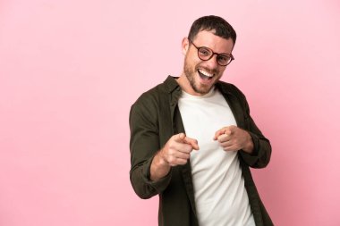 Pembe arka planda izole edilmiş genç Brezilyalı adam öne bakıyor ve gülümsüyor.