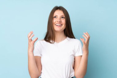 Mavi arka planda izole edilmiş genç beyaz kız bunalıma girmiş.