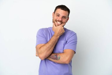 Genç Brezilyalı adam beyaz arka planda yalnız mutlu ve gülümsüyor.