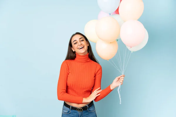 Junge Frau Fängt Viele Luftballons Auf Blauem Hintergrund Und Lacht — Stockfoto