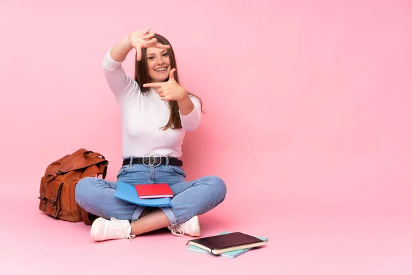 Adolescente Menina Estudante Caucasiano Sentado Chão Isolado Fundo Rosa Focando — Fotografia de Stock