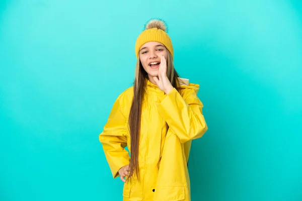 Κοριτσάκι Φορώντας Αδιάβροχο Παλτό Πάνω Από Απομονωμένο Μπλε Φόντο Φωνάζοντας — Φωτογραφία Αρχείου