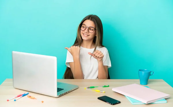 Menina Uma Mesa Com Laptop Sobre Fundo Azul Isolado Apontando — Fotografia de Stock