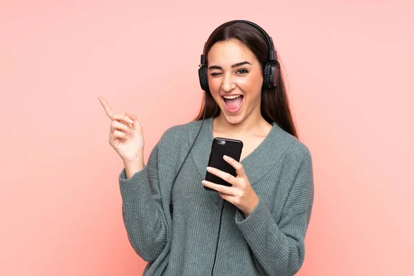 Joven Mujer Caucásica Aislada Sobre Fondo Rosa Escuchando Música Con —  Fotos de Stock