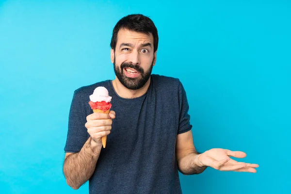 Junger Mann Mit Einem Kornetteis Über Isoliertem Blauem Hintergrund Unglücklich — Stockfoto