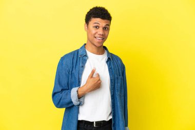 Genç Afrikalı Amerikalı adam, sarı arka planda, şaşırmış yüz ifadesi ile izole edilmiş.