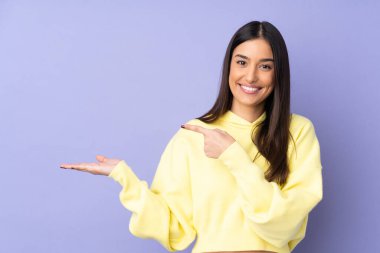 İzole edilmiş arka plan üzerinde genç beyaz kadın bir ilan vermek için avucunun içinde hayali bir mekan tutuyor.