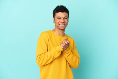 Genç Afrikalı Amerikalı adam mavi arka planda izole edilmiş gülüyor.
