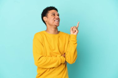 Genç Afrikalı Amerikalı bir adam mavi arka planda izole edildi.