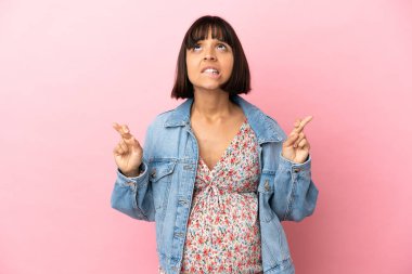 Genç hamile kadın pembe arka planda, şans diliyor ve en iyisini diliyor.