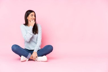 Pembe arka planda izole edilmiş genç beyaz kadın gergin ve korkmuş.